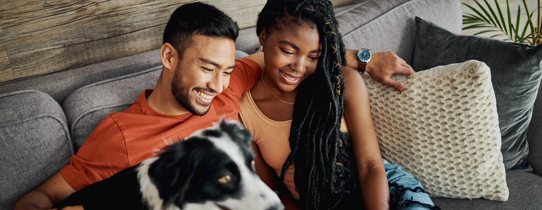 a man and woman sitting on a couch with a dog