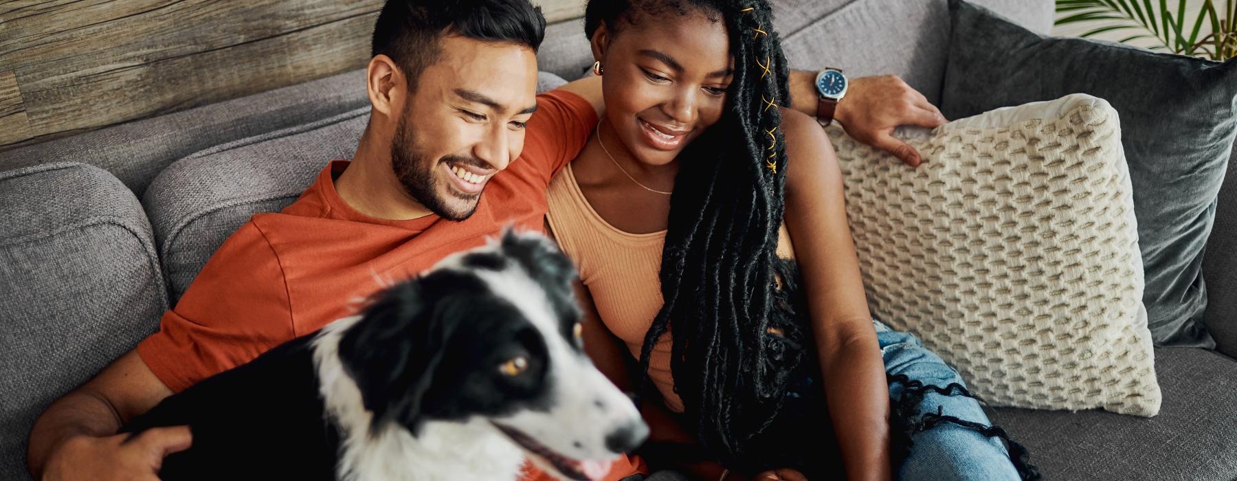 a man and woman sitting on a couch with a dog