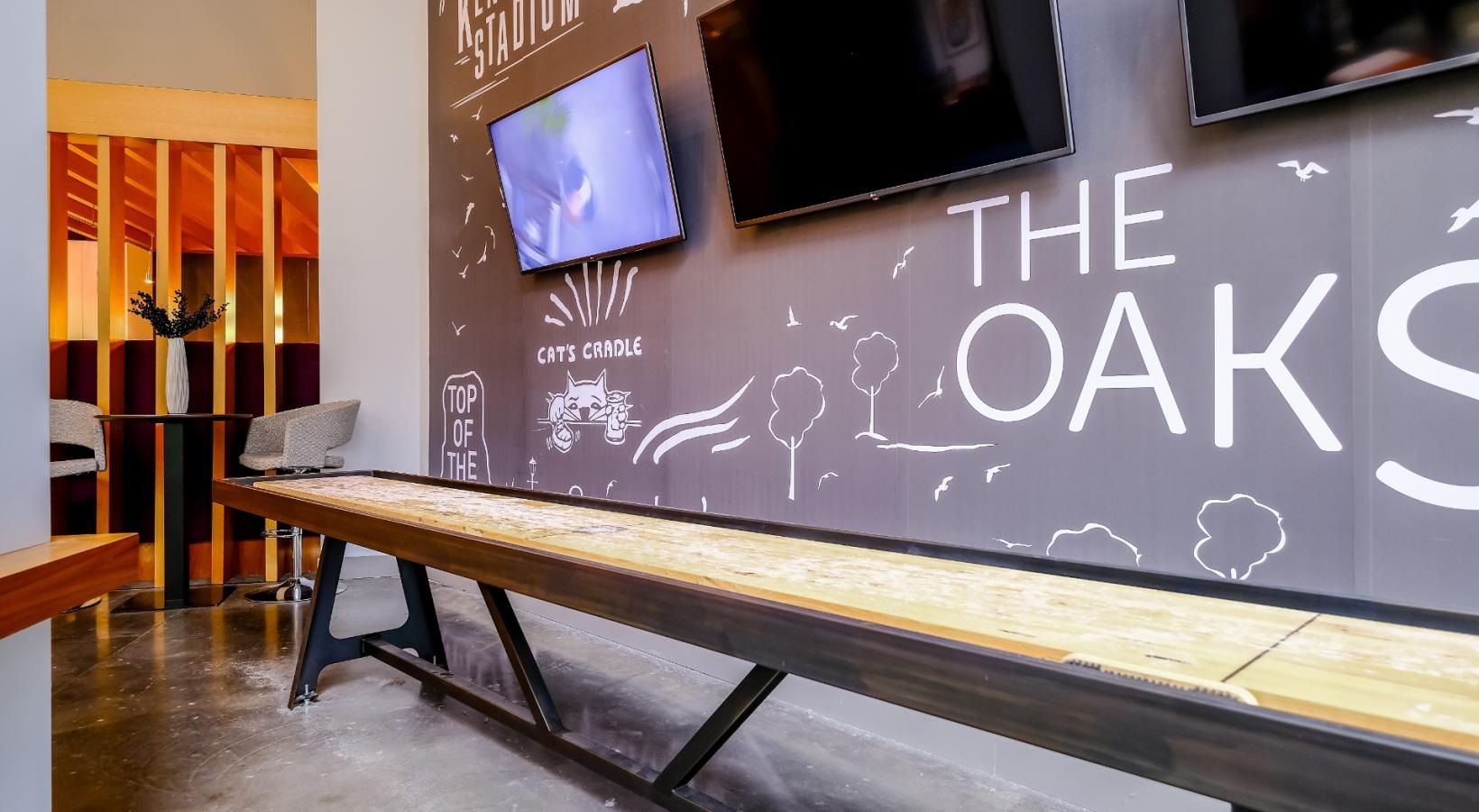 Access to resident-only features a room with tvs on a wall and a shuffleboard table